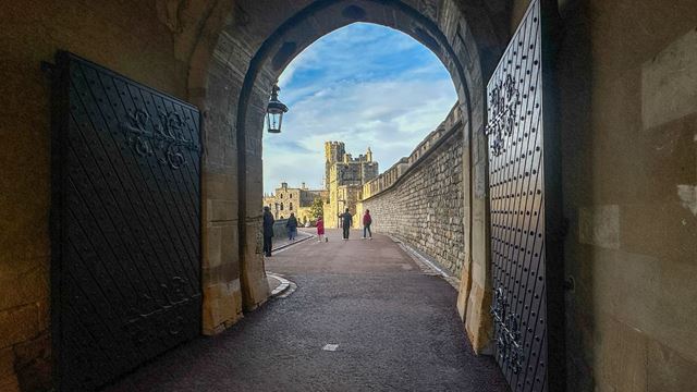 An open gate at windsor castle with buildings and blue sky in the distance.