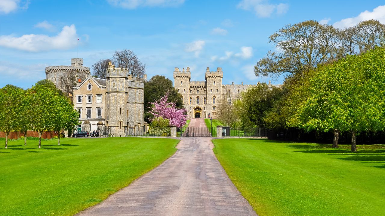 Windsor Castle and the luscious green gardens surrounding the grounds. © Shutterstock. External shot of Windsor Castle and the surrounding green grounds.