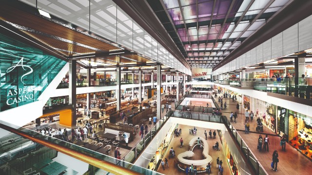 Bird's-eye view of the interior of Westfield Stratford City in east London, a modern shopping mall. Many people walk between shops and the glass fronts of retail outlets.