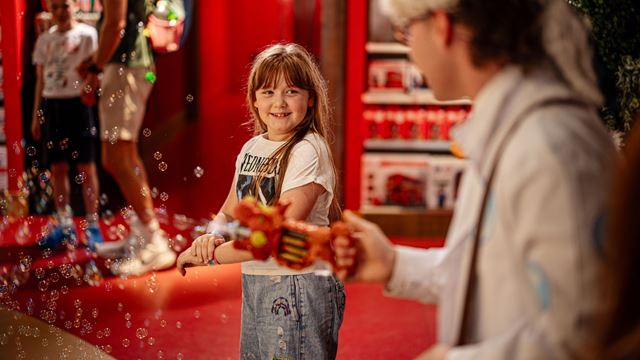 Hamleys store work releasing bubbles from a toy with a child in the background.