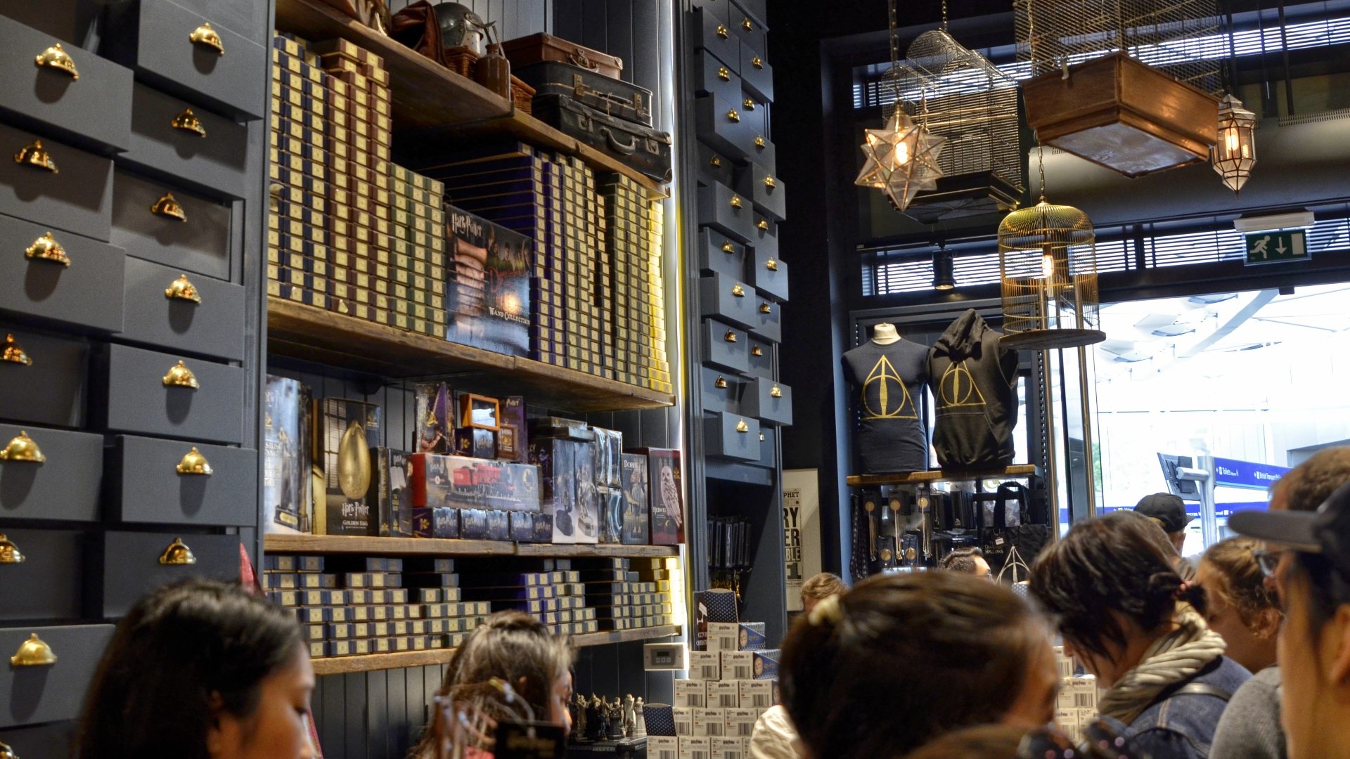People stood inside the Harry Potter shop in King's Cross with messy drawers reaching the ceilings and stacks of boxes and trinkets that look like they came from the film