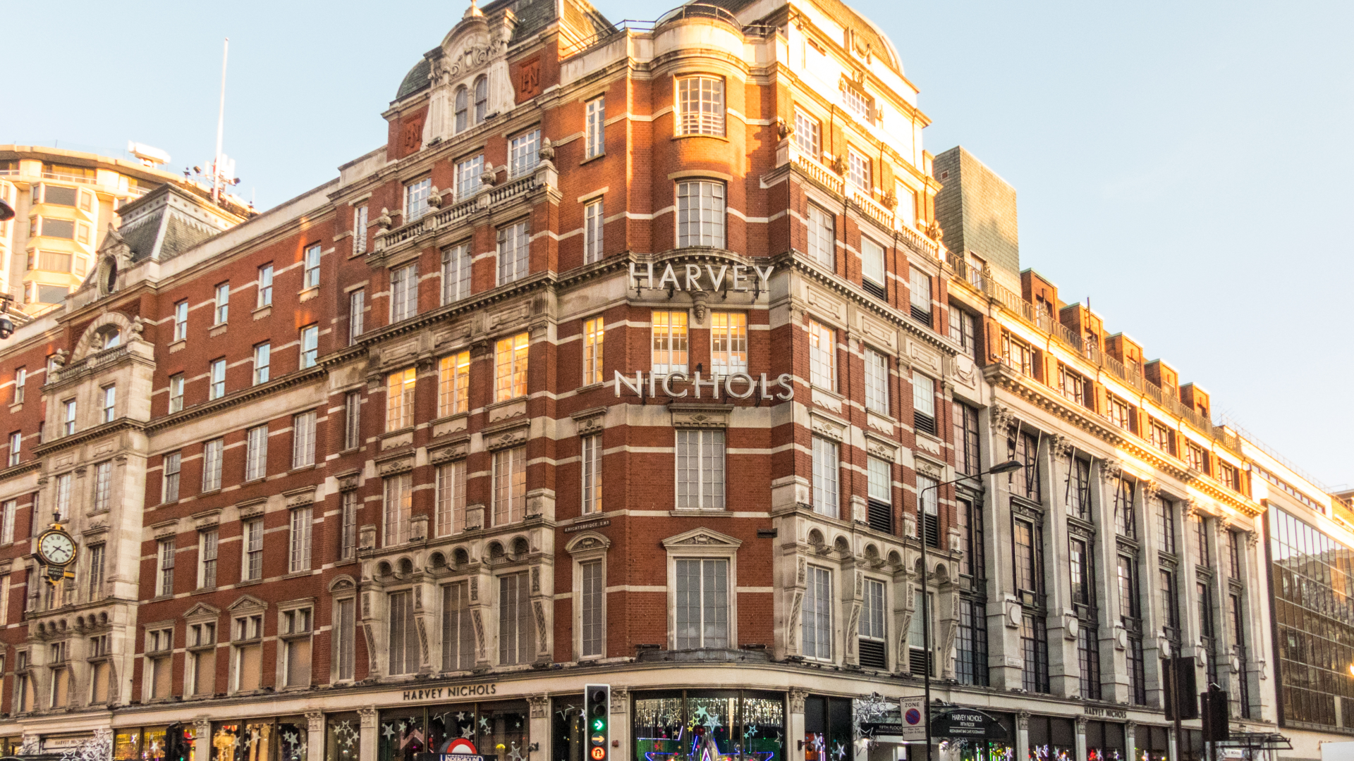 A photo of the exterior of Harvey Nichols in Knightsbridge on a sunny afternoon with people walking outside on the streets