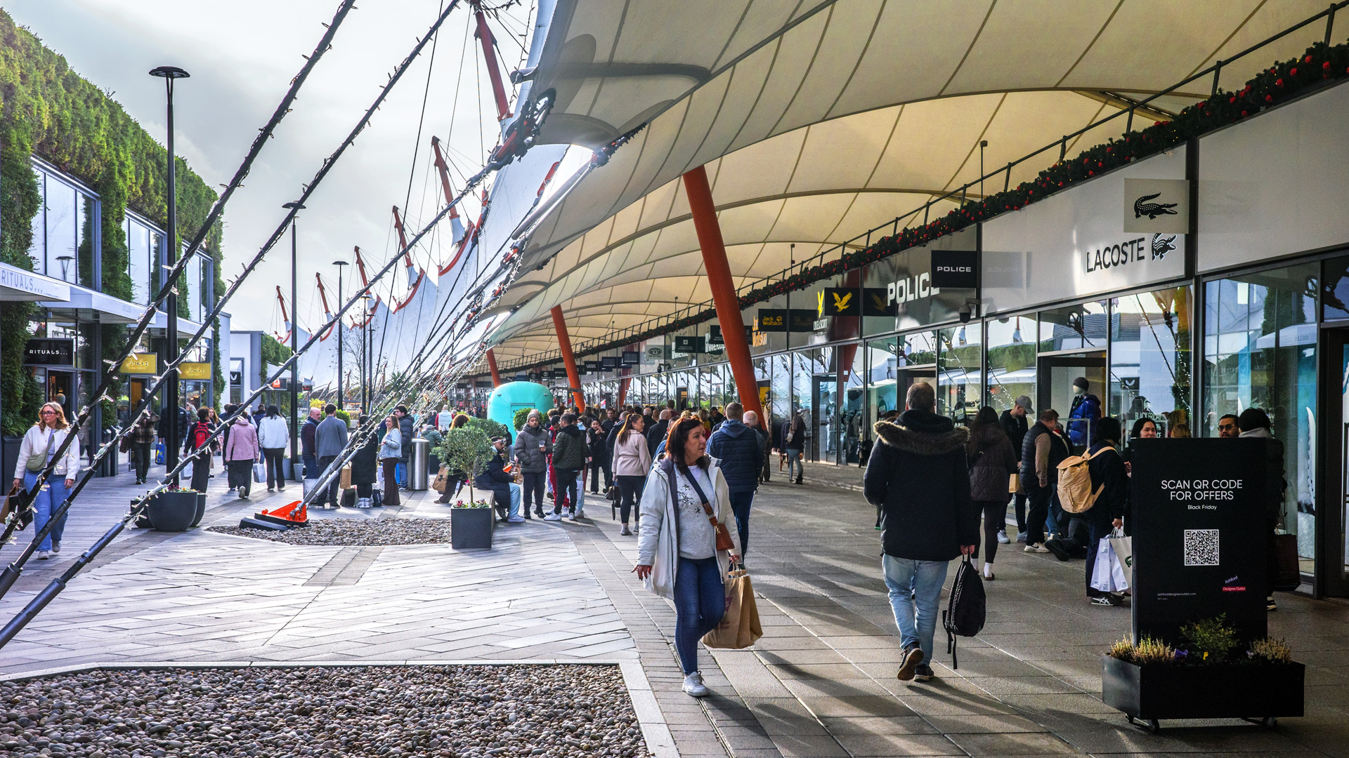 The exterior of Ashford Designer Outlet with people shopping on a sunny day