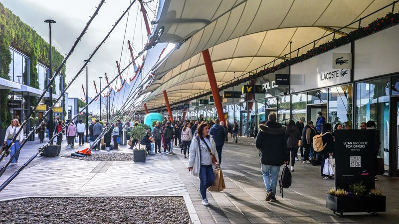 Experience relaxed outlet shopping at Designer Outlet Ashford, with big savings on well-known brands and a spacious open-air setting. Image courtesy of Shutterstock. The exterior of Ashford Designer Outlet with people shopping on a sunny day