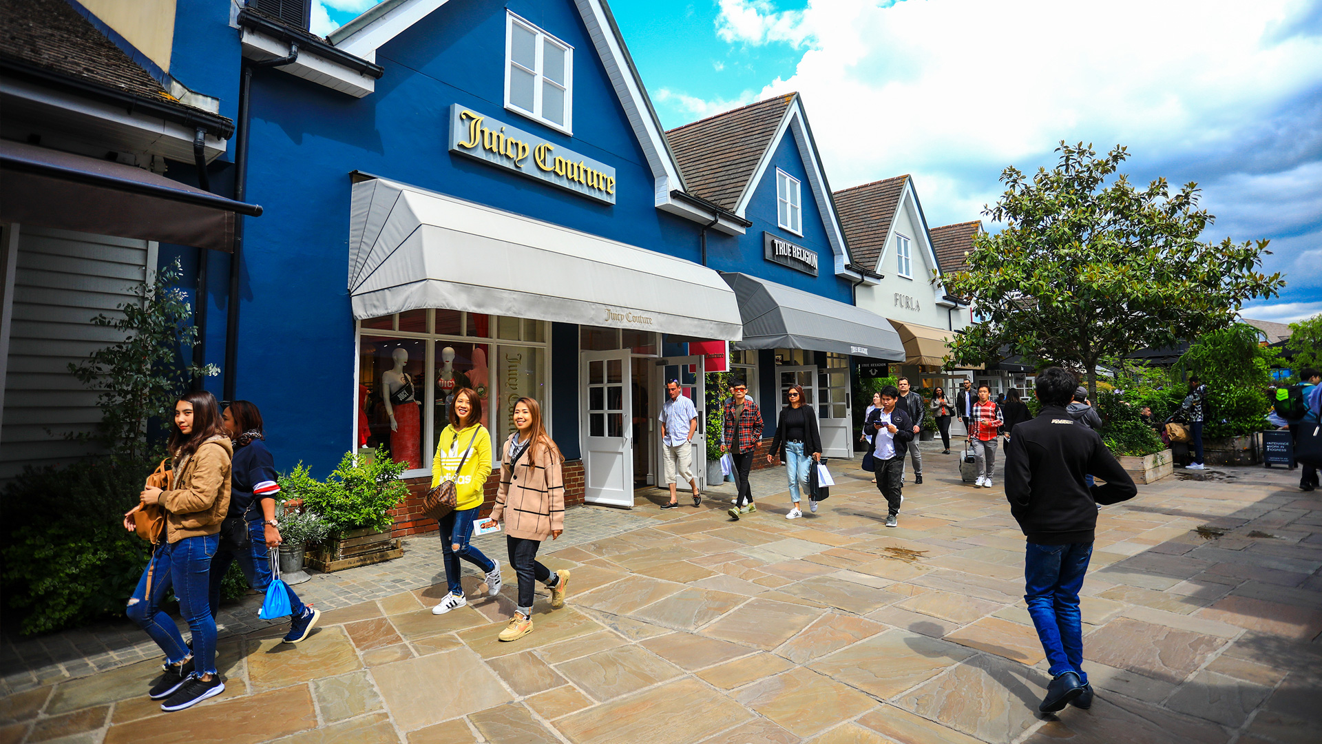 People walking past a row of colourful shops on a sunny day