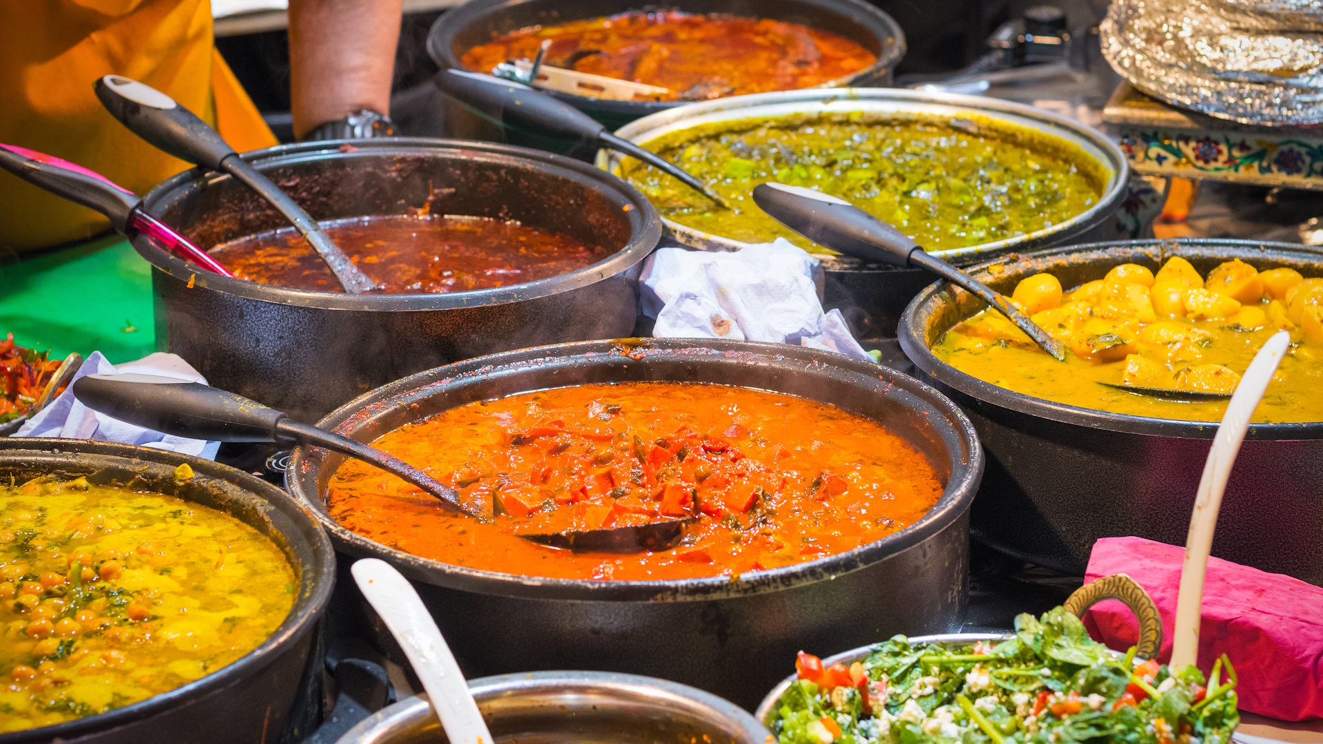 A variety of colourful Indian curries on display at Brick Lane Market in London.