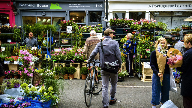 A person with a bicycle browses the flower-filled stalls of Columbia Road Flower Market