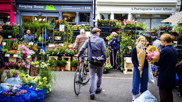 A man with a bicycle browses the flower-filled stalls of Columbia Road Flower Market.