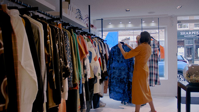 Eine Frau stöbert in den Kleiderstangen der 69b Boutique.