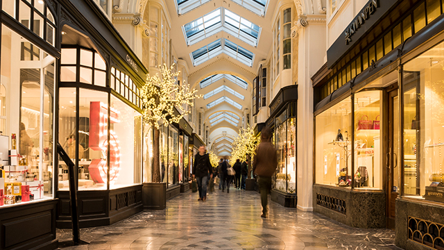 Looking along Burlington Arcade, with little shops and Christmas decorations either side and people further along the arcade.