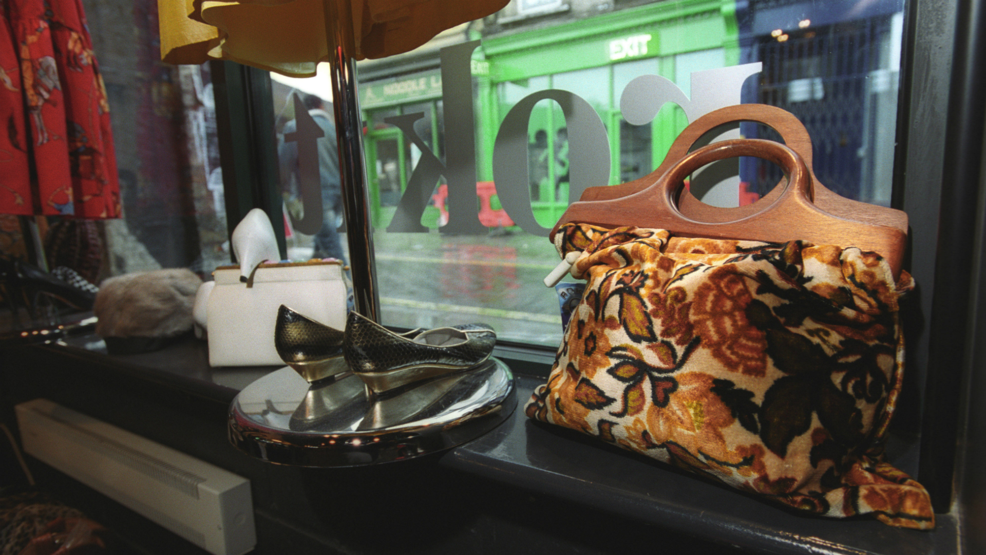 A vintage orange and brown retro bag and black shows in the window display at Rokit.