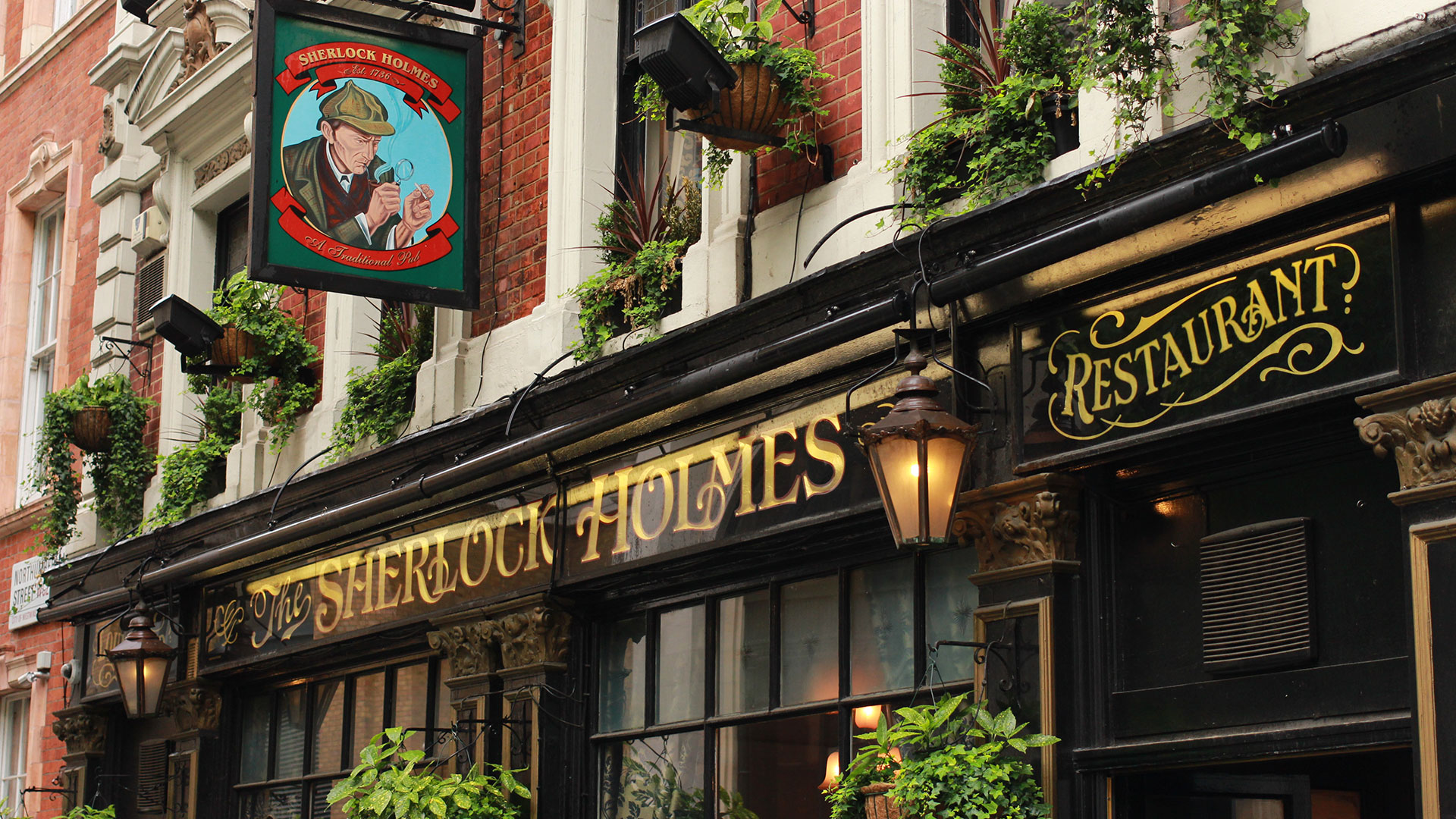 The black and gold Sherlock Holmes pub facade, with pub sign displaying a drawing of the famous detective.