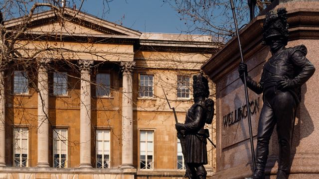 The exterior of Apsley House with its famous columns, with a memorial to the Duke of Wellington in the foreground.