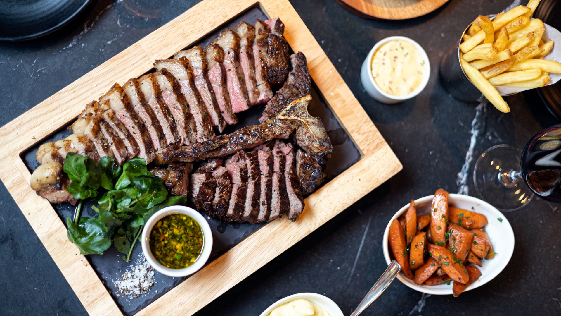 A sharing board of sliced steak with sauces and sides at Bread Street Kitchen in Battersea.