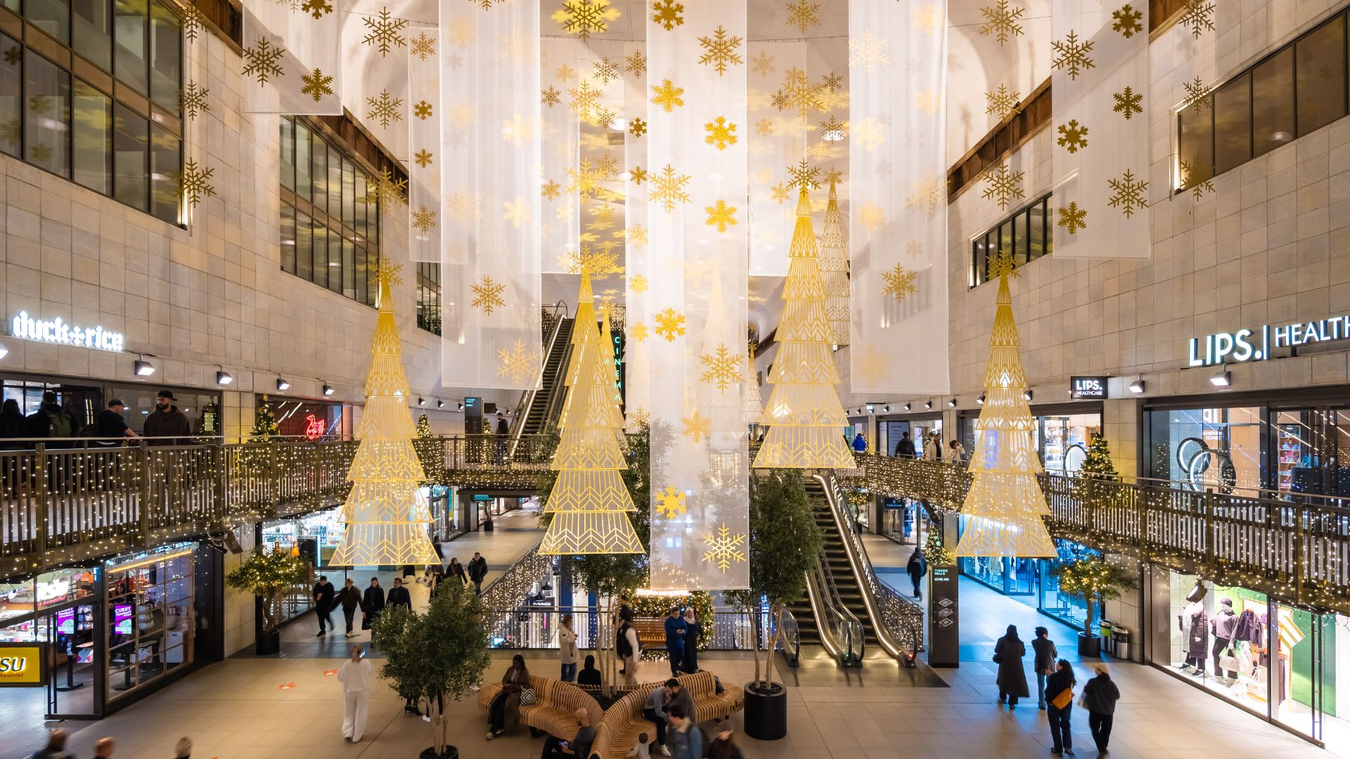 Festive gold decorations and illuminated trees hanging inside the Turbine Hall at Battersea Power Station.