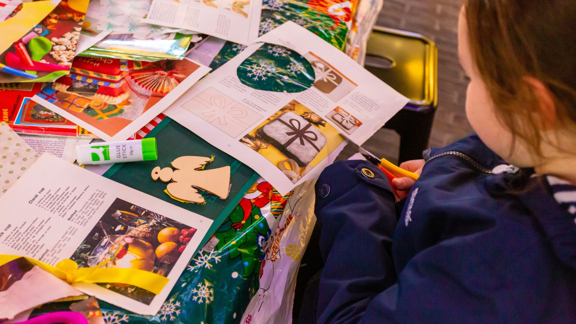 A child taking part in a Christmas craft workshop, surrounded by colourful paper, scissors and festive materials at Battersea Power Station.
