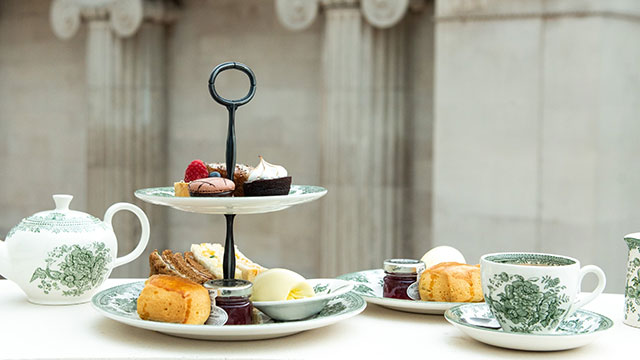 Une sélection de scones et petits gateaux sont disposés sur un présentoir accompagné de thé.