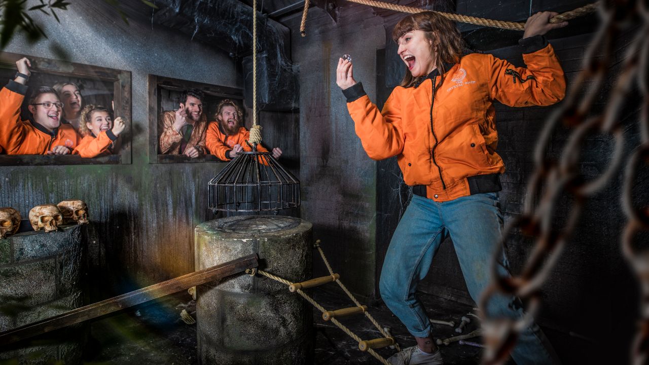 Explore the scary medieval time zone. Image courtesy of The Crystal Maze LIVE Experience. Group of people in orange jackets exploring the medieval-themed set of The Crystal Maze LIVE Experience in London.