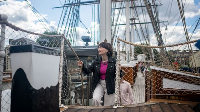 A woman is climbing the stairs to reach the top deck of the Cutty Sark, the iconic ship docked in Greenwich.