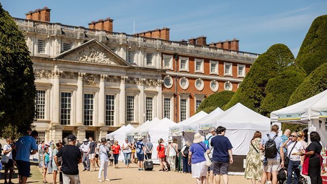 People wander food stalls and tents in front of hampton court palace at the hampton court palace food festival.
