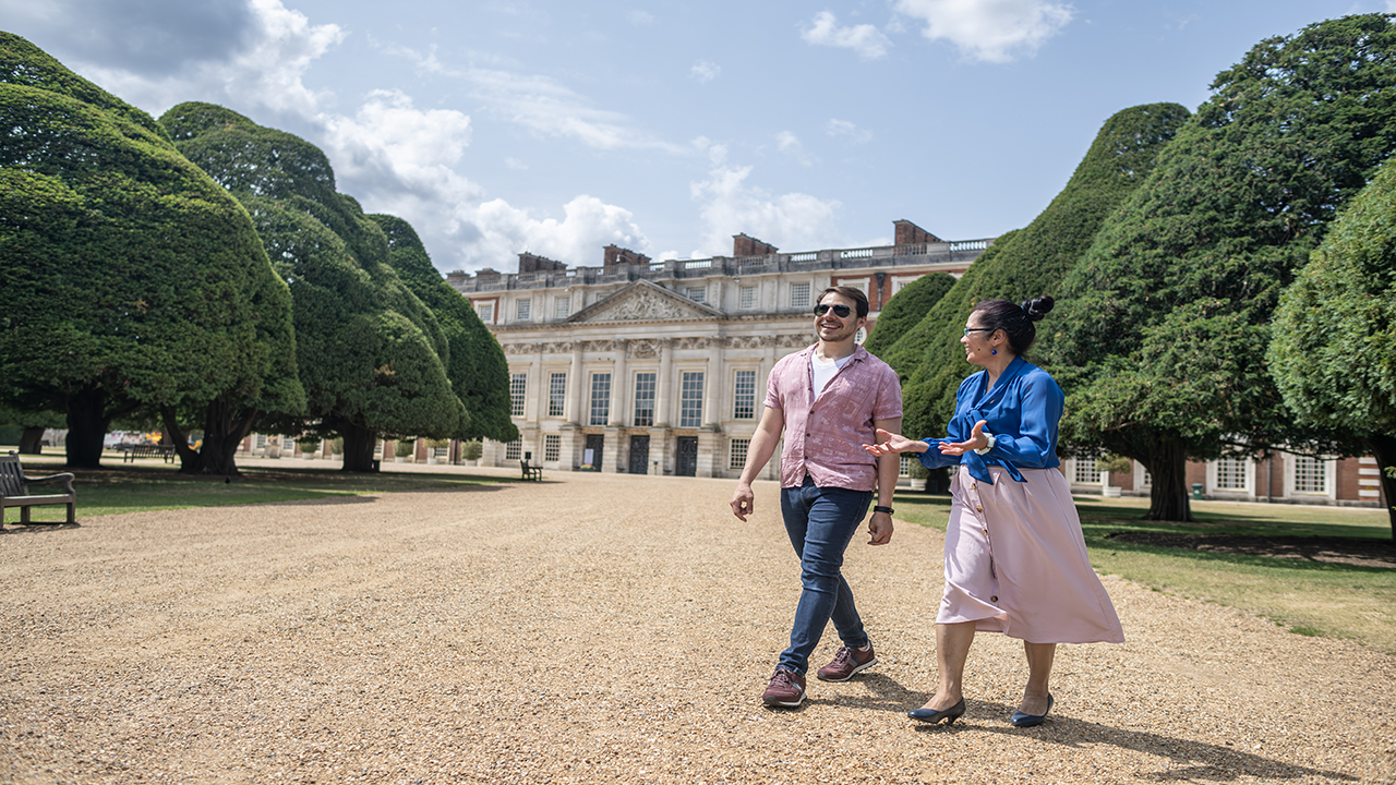 Promenez-vous dans les jardins mondialement connus du palais de Hampton Court, qui abrite le plus ancien labyrinthe à énigmes. ©London & Partners/Michael Barrow Deux amis profitent du temps ensoleillé au palais de Hampton Court et se promènent dans les fameux jardins du domaine.