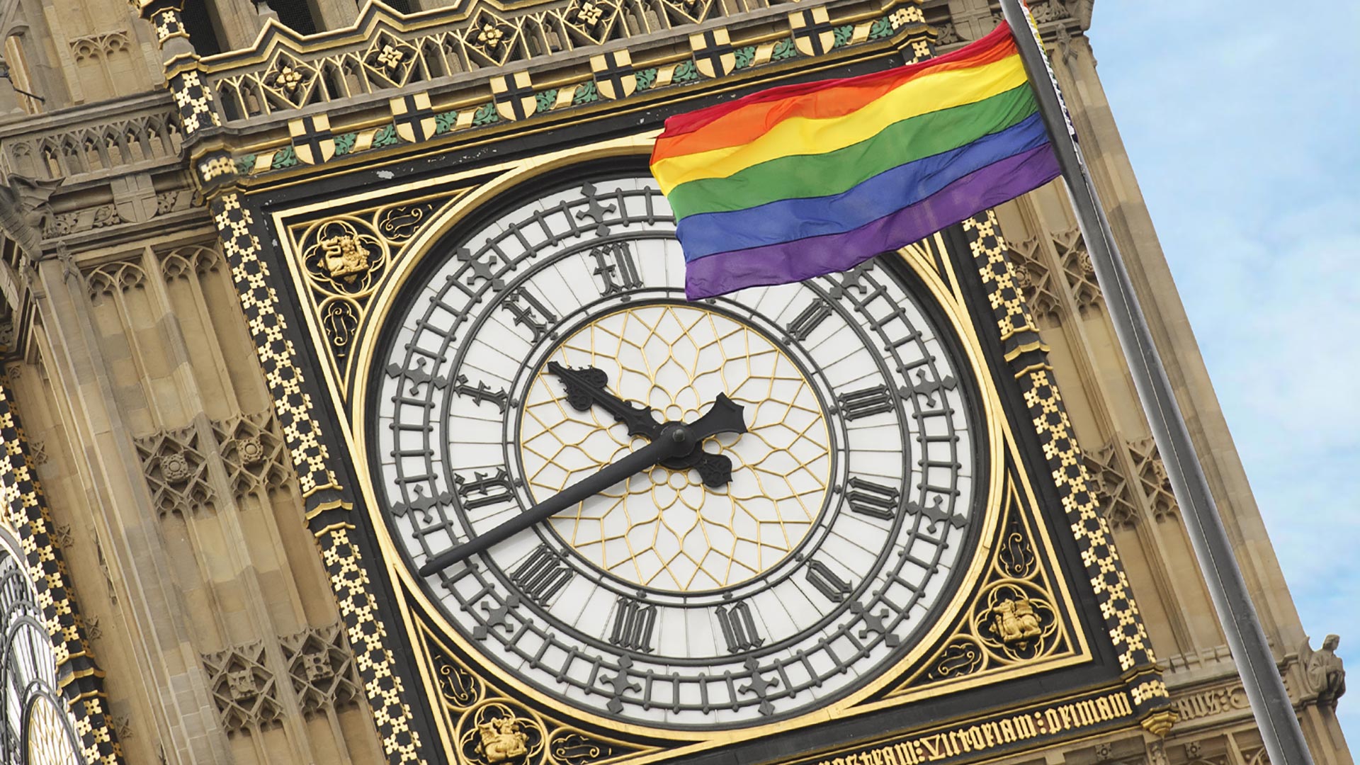 Elizabeth Tower, also known as Big Ben, with an LGBT+ flag on the clock face.