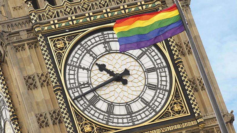 Celebrate LGBTQ+ History Month in London. Image courtesy of UK Parliament. Elizabeth Tower, also known as Big Ben, with an LGBT+ flag on the clock face.