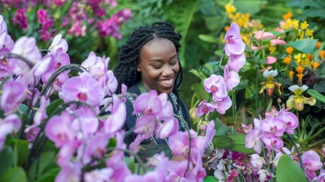 A woman stands among the orchids festival at Kew Gardens. 