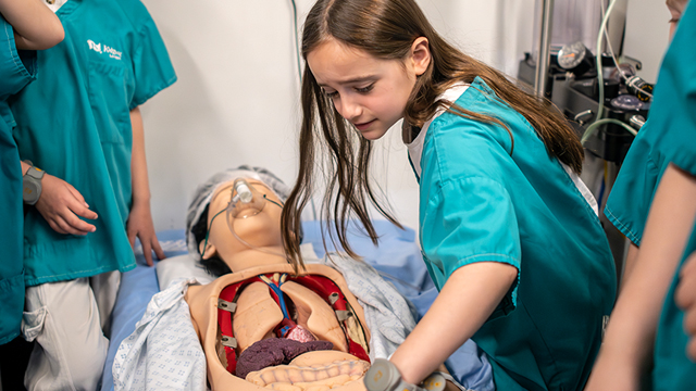 Laissez les enfants découvrir les professions médicales à KidZania Londres. Avec l'aimable autorisation de © visitlondon.com/Michael Barrow Une jeune fille porte une blouse verte et semble jouer le rôle du chirurgien dans la salle d'opération de KidZania Londres.