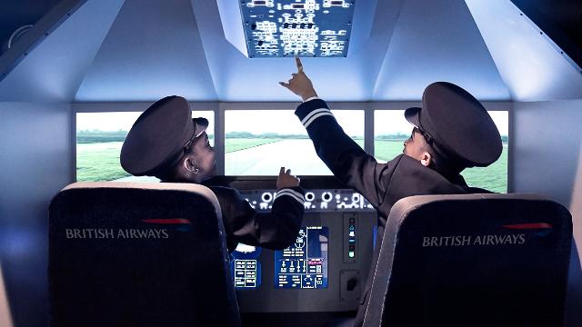 Kinder vergnügen sich bei den Flugaktivitäten im KidZania. Bild mit Genehmigung von KidZania London. Zwei Jungen in Pilotenuniformen sitzen im Cockpit eines Flugzeugs bei Kidzania.