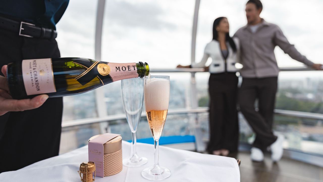 Enjoy 360-degree views of London with a trip on the London Eye. © London & Partners/Michael Barrow. Two people walk in front of the pods of the London Eye.