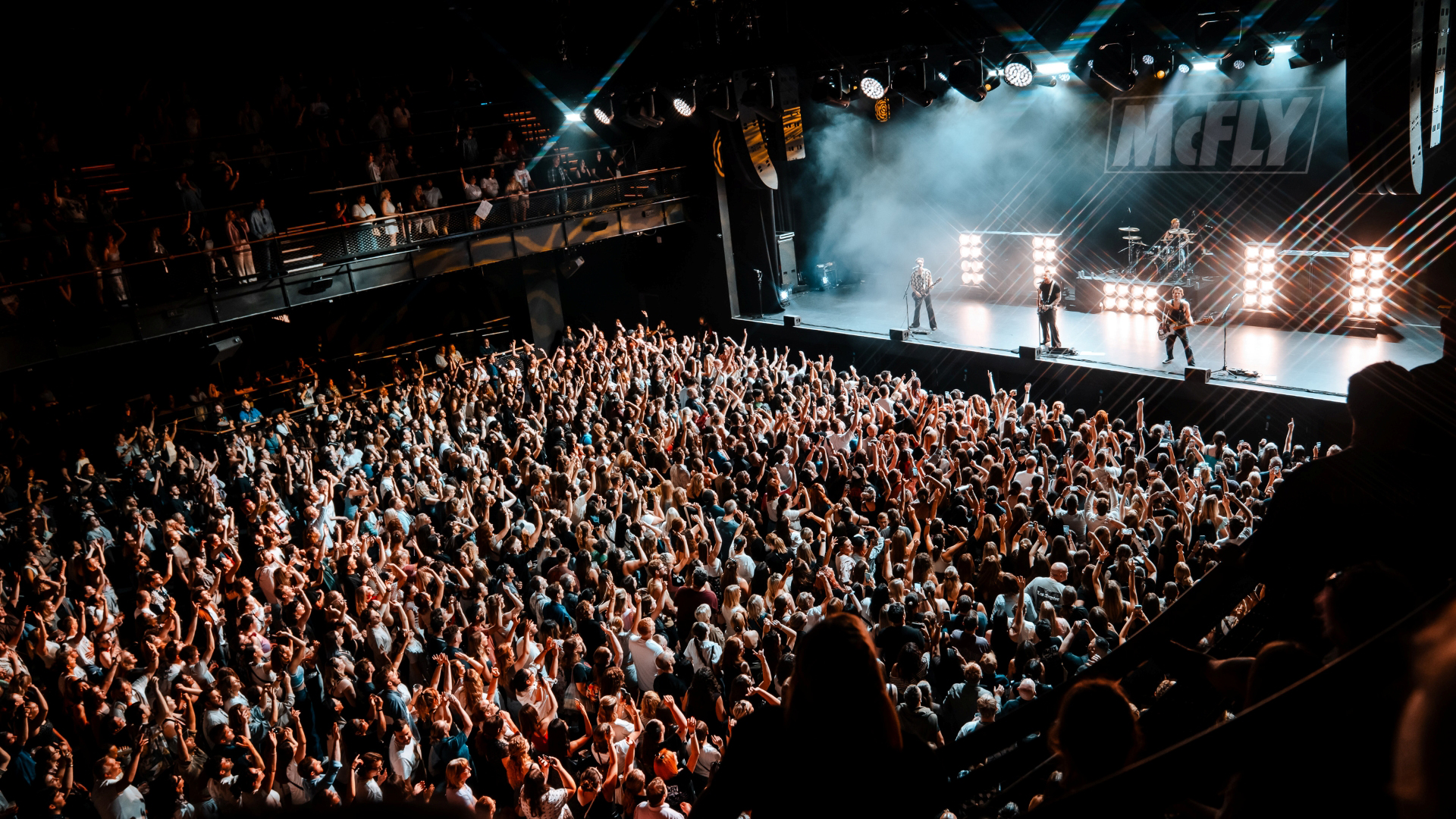 A photo of the crowd at Blues Kitchen in Camden. Everyone is smiling with their hands in the air facing the stage as confetti falls from above
