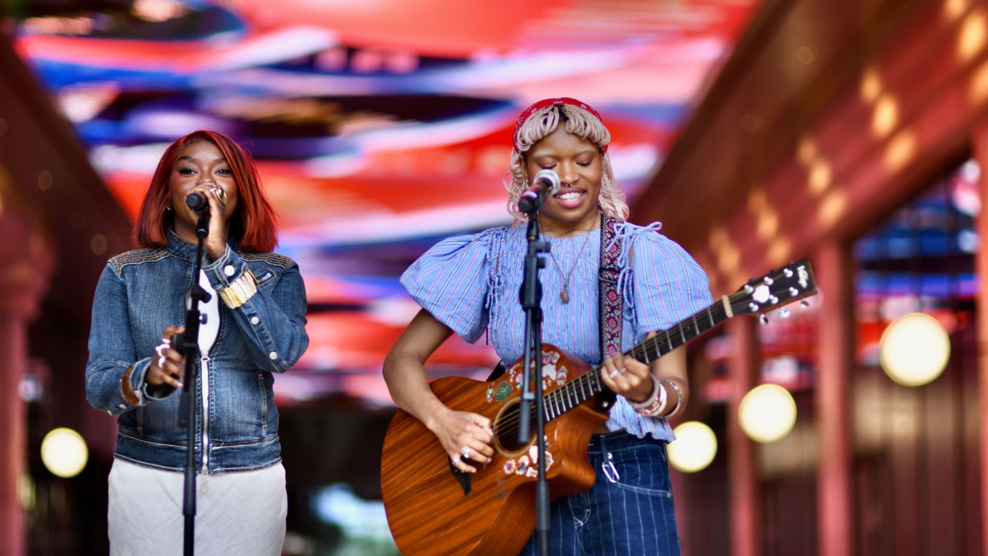 Two musicians perform on stage at Olympia, singing and playing guitar beneath colourful lights during a live music event. Image courtesy of Olympia.