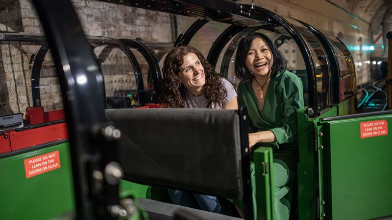 Travel back in time with a visit to the Postal Museum and discover how mail was delivered using underground tunnels in London. Credit: Michael Barrow. Image courtesy of London & Partners. Two women are sitting on the rail mail ready to depart at the Postal Museum.