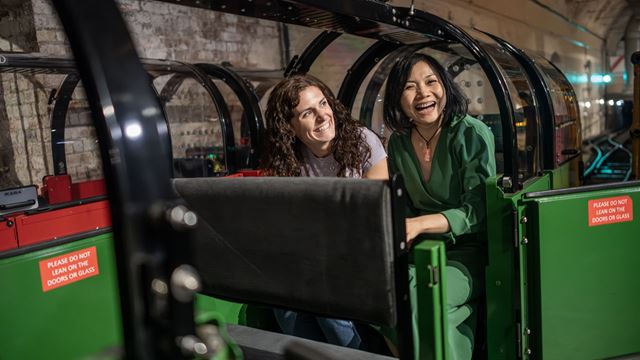 Two women are sitting on the rail mail ready to depart at the Postal Museum. 