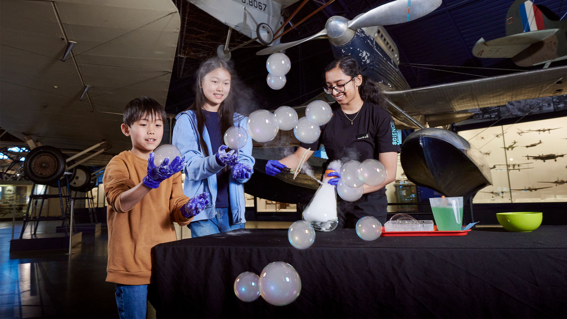 Astronights at the Science Museum. Image courtesy of the Science Museum Group. Bubbles flying in the air and people with gloves holding them at the Science Museum.