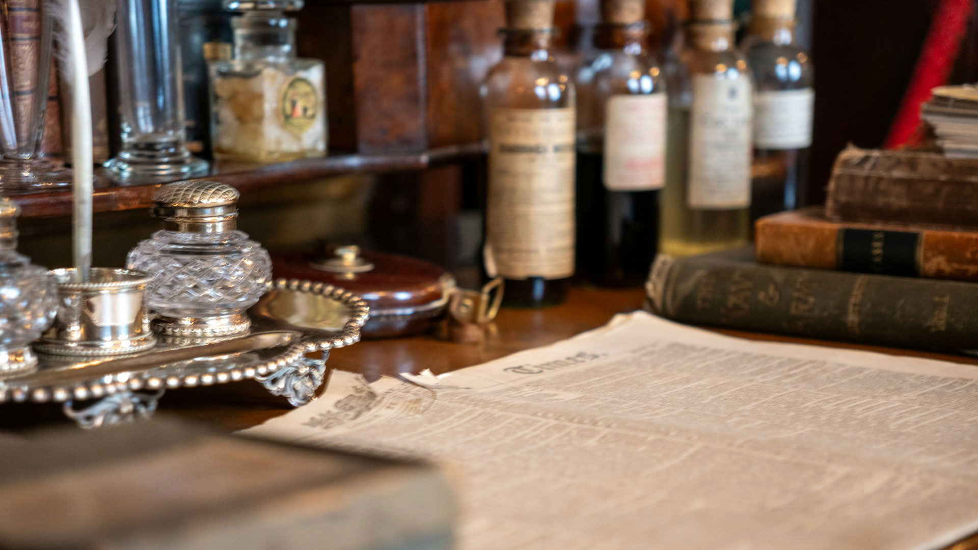 Old newspaper, glass bottles and books on display inside The Sherlock Holmes Museum in London.