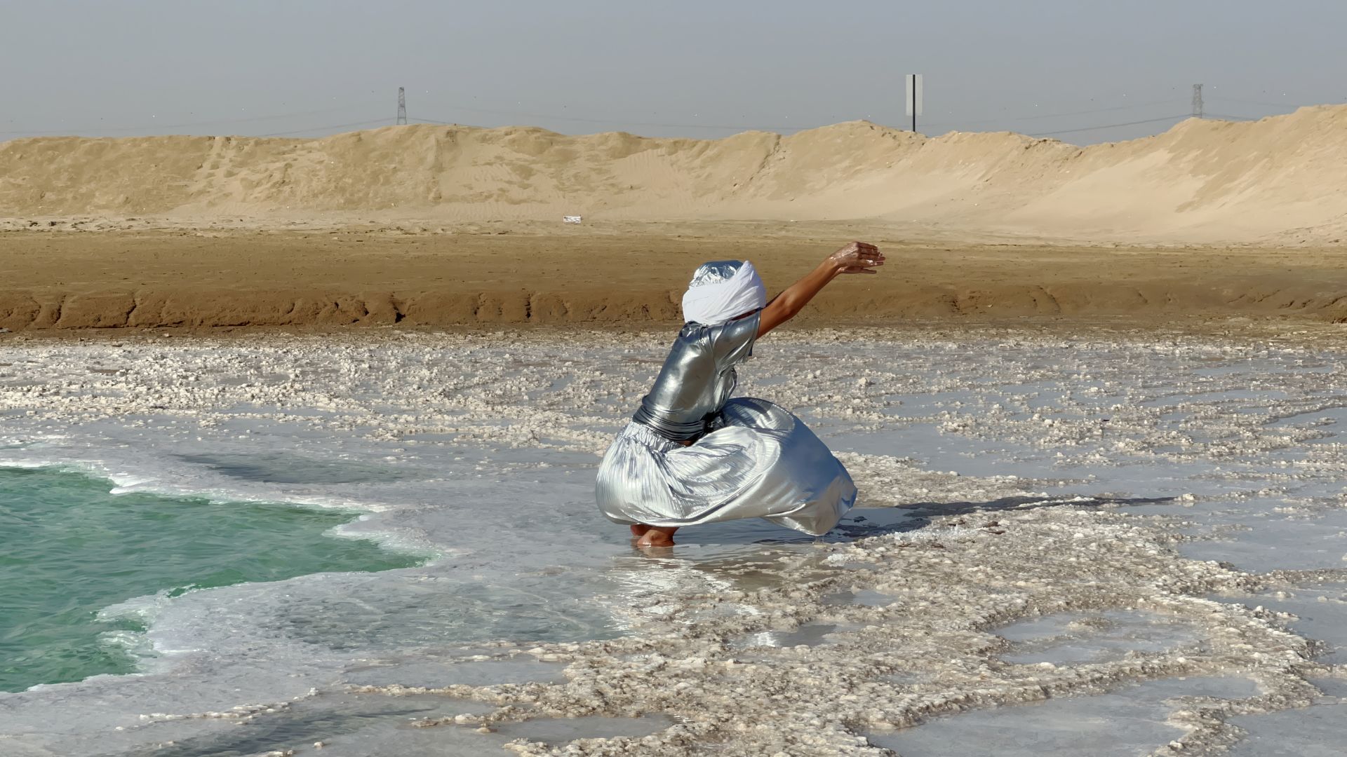 Salt Cosmologies by HylozoicDesires, Soap of the Sages, Sun of the Sea at Somerset House. Image courtesy of Somerset House. AI enhanced imagery of person crouching down in middle of salt lake.