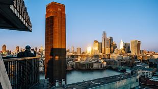 Person standing on the Tate Modern viewing terrace taking a picture of the landmarks in the distance.