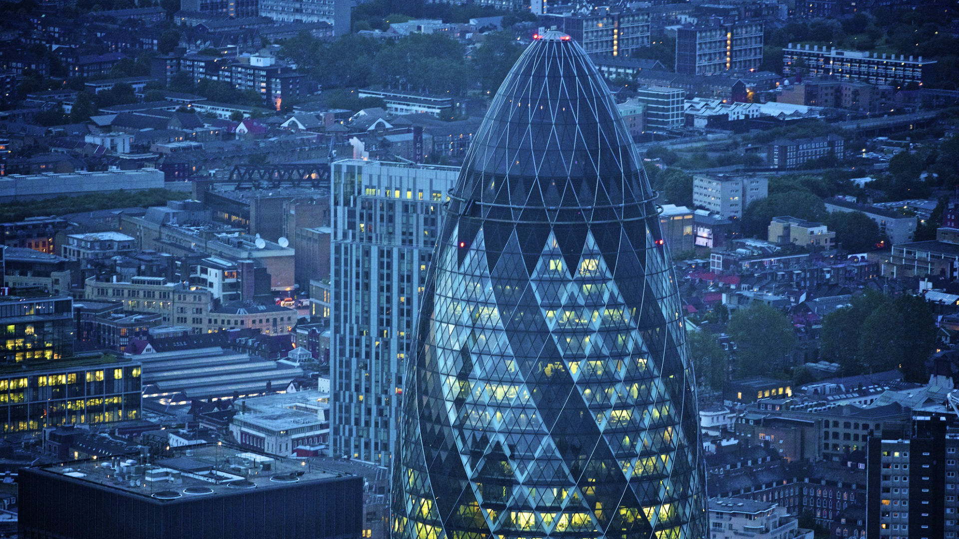 An aerial shot of The Gherkin and the City of London lit up at night. © petewebb.com/London and Partners   