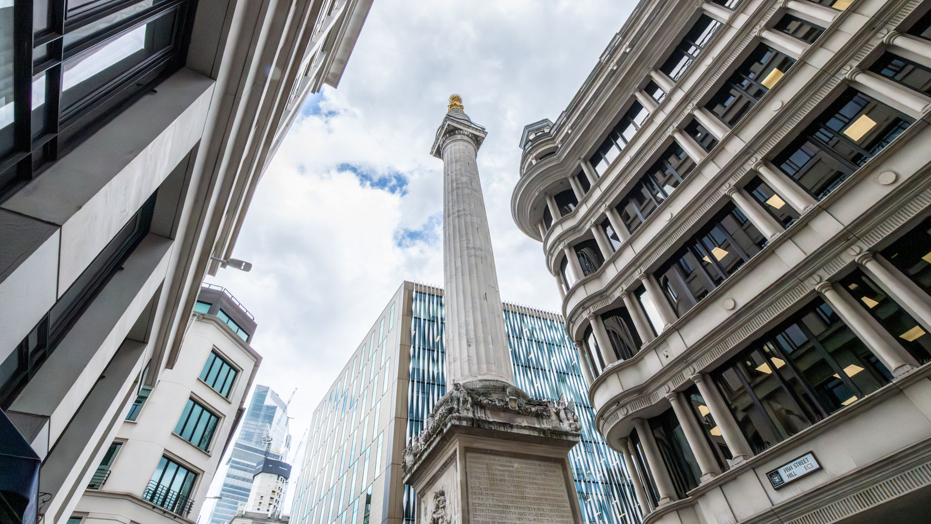 A view looking up at The Monument, with modern buildings either side.