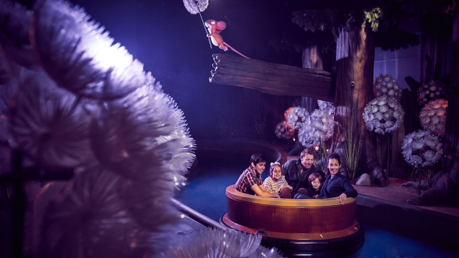 A family-friendly slow river ride adventure, with two adults and three children smiling and looking at The Gruffalo themed attraction.