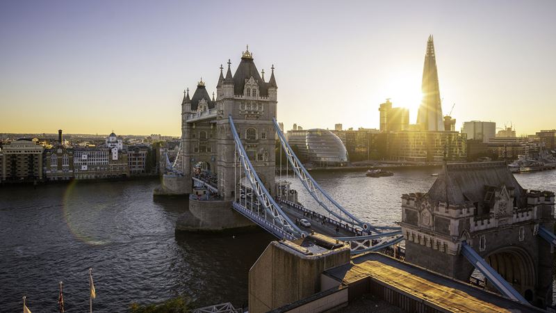A panoramic view of Tower Bridge and the Thames at sunset, with City Hall and The Shard in the background.
