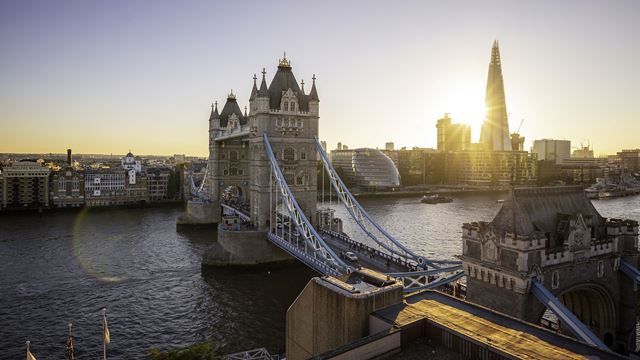 A panoramic view of Tower Bridge and the Thames at sunset, with City Hall and The Shard in the background.