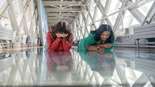 Deux femmes sont absorbées par la vue depuis la passerelle en verre de Tower Bridge. 