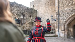 Ein weiblicher Beefeater leitet eine Führung im Tower of London.