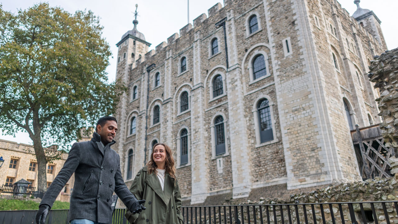 Lors d’une visite guidée, découvrez l’époque durant laquelle la Tour de Londres était considérée comme étant la prison la plus infame d’Angleterre. ©London & Partners/Michael Barrow Un homme et une femme passent à côté de la Tour Blanche, bâtiment situé au centre de la Tour de Londres.