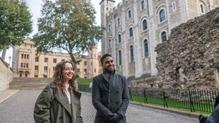 Un homme et une femme écoutent les commentaire de leur guide lors d'une visite de la Tour de Londres.