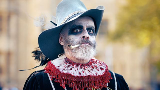A costumed performer dressed as a sinister cowboy-style character looks towards the camera.