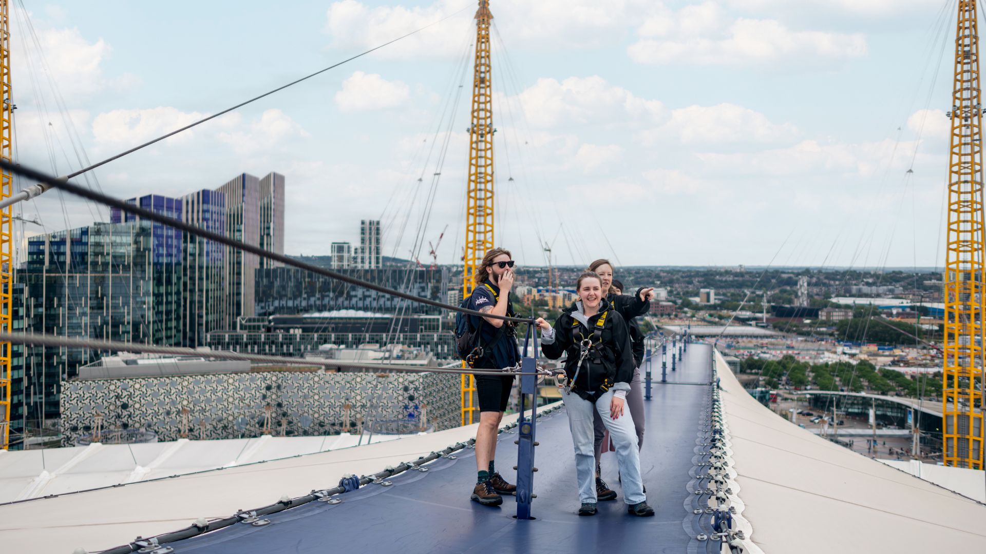 A group of climbers stand together on top of The O2’s roof, surrounded by London’s skyline.